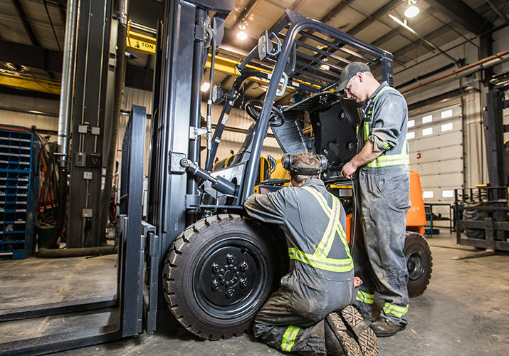 Teknisi melakukan service forklift di workshop